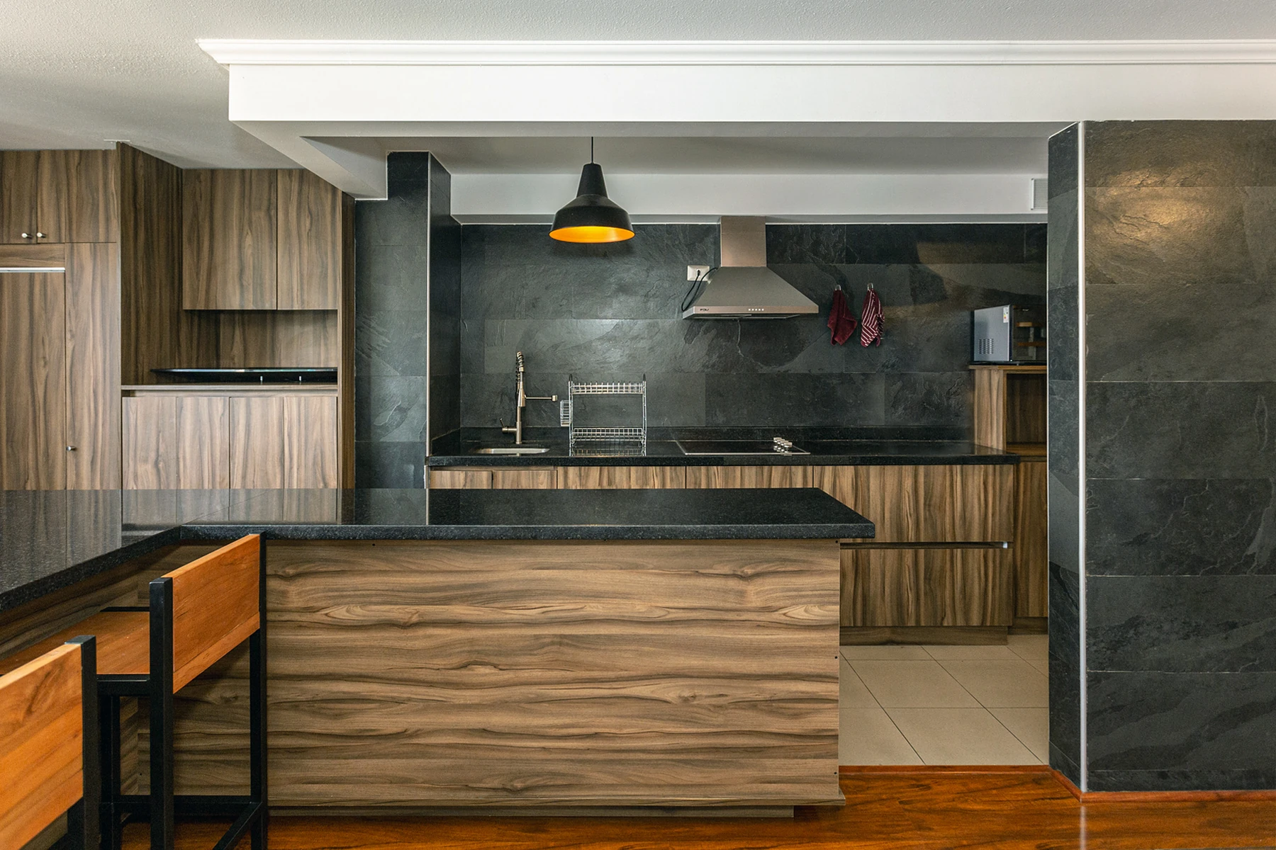 Cocina con muebles de madera, isla central y revestimientos de piedra oscura